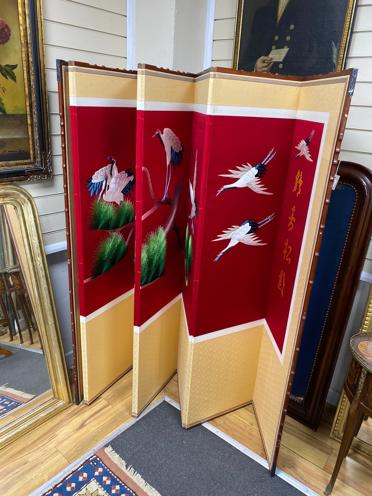 A modern Chinese faux bamboo embroidered eight fold dressing screen decorated with cranes, each panel 43cm x 176cm.